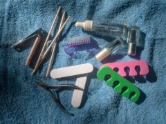 Akcesoria do manicure na niebieskim ręczniku, w tym pilniki i preparaty kosmetyczne
