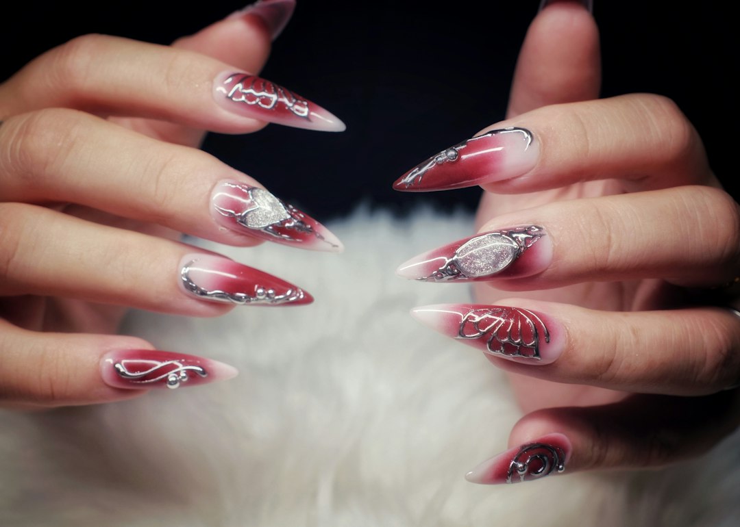 Dłonie z długimi czerwono-białymi paznokciami stiletto