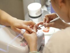 Wykonywanie manicure na dłoniach klientki w salonie paznokci