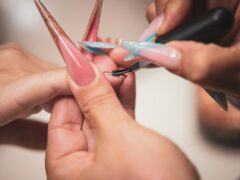 Stylistka maluje długie paznokcie w czasie zabiegu manicure